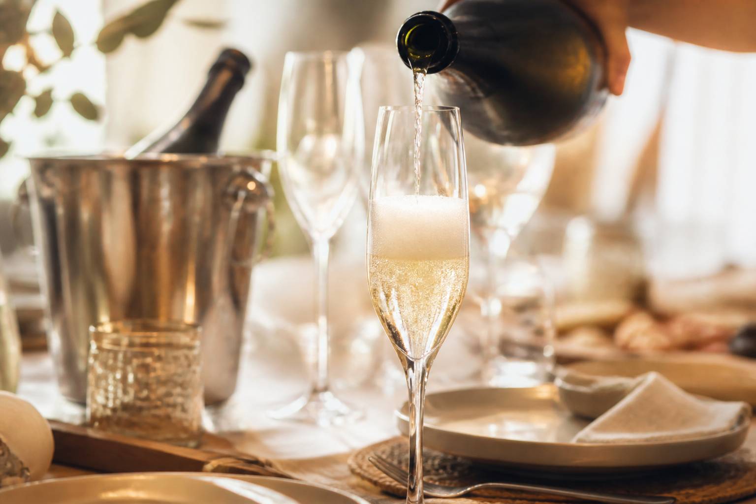 Champagne versé dans une flûte avec des bulles près d'un seau à glace